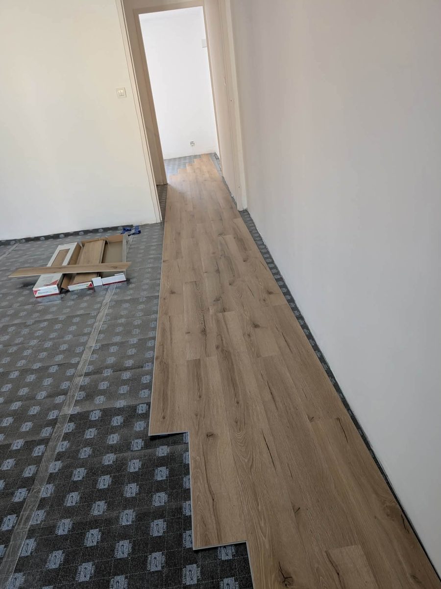 Pose de sol stratifié en cours sur sous-couche, couloir et pièce
